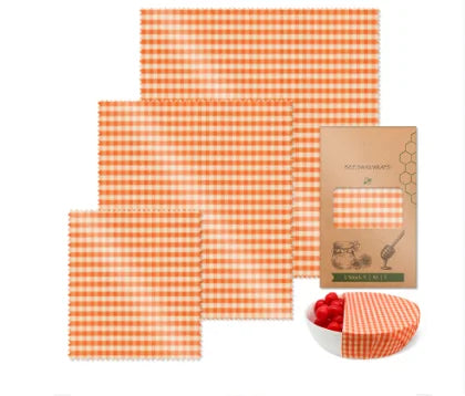 Orange and white checkered reusable beeswax food wrap in various square sizes for plastic-free kitchen storage.