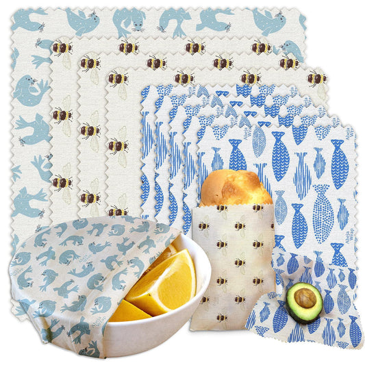 Assorted reusable beeswax wraps with bird, bee, and fish patterns covering food items.