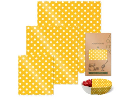 Yellow polka dot reusable beeswax food wrap for plastic-free kitchen storage with packaging and a covered bowl.