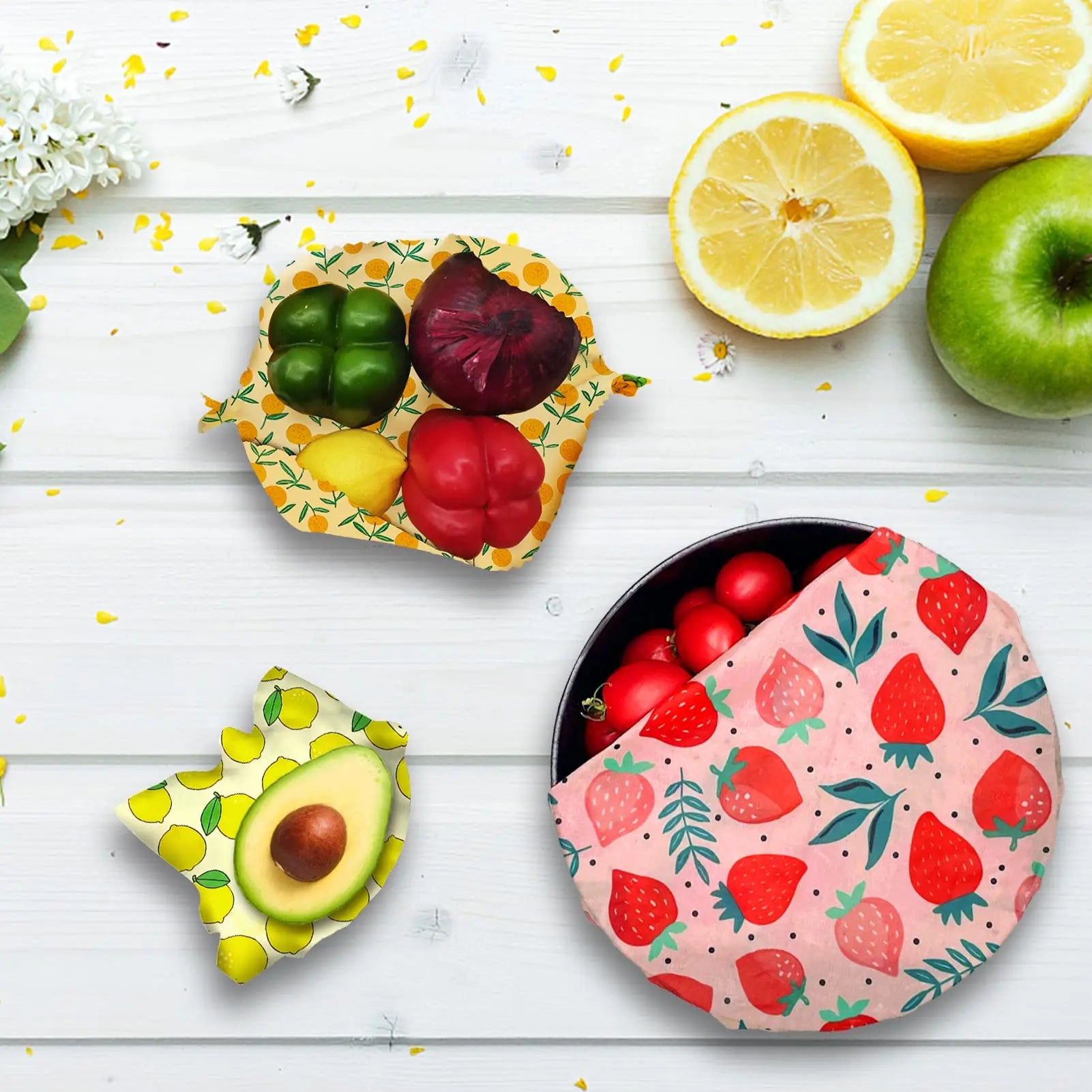 Reusable beeswax food wrap for plastic-free kitchen storage, featuring lemon and strawberry patterns with fresh produce.