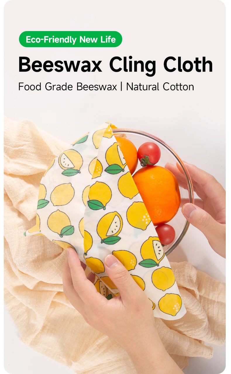 Reusable beeswax food wrap with yellow lemon pattern covers a bowl of fruit for plastic-free kitchen storage.